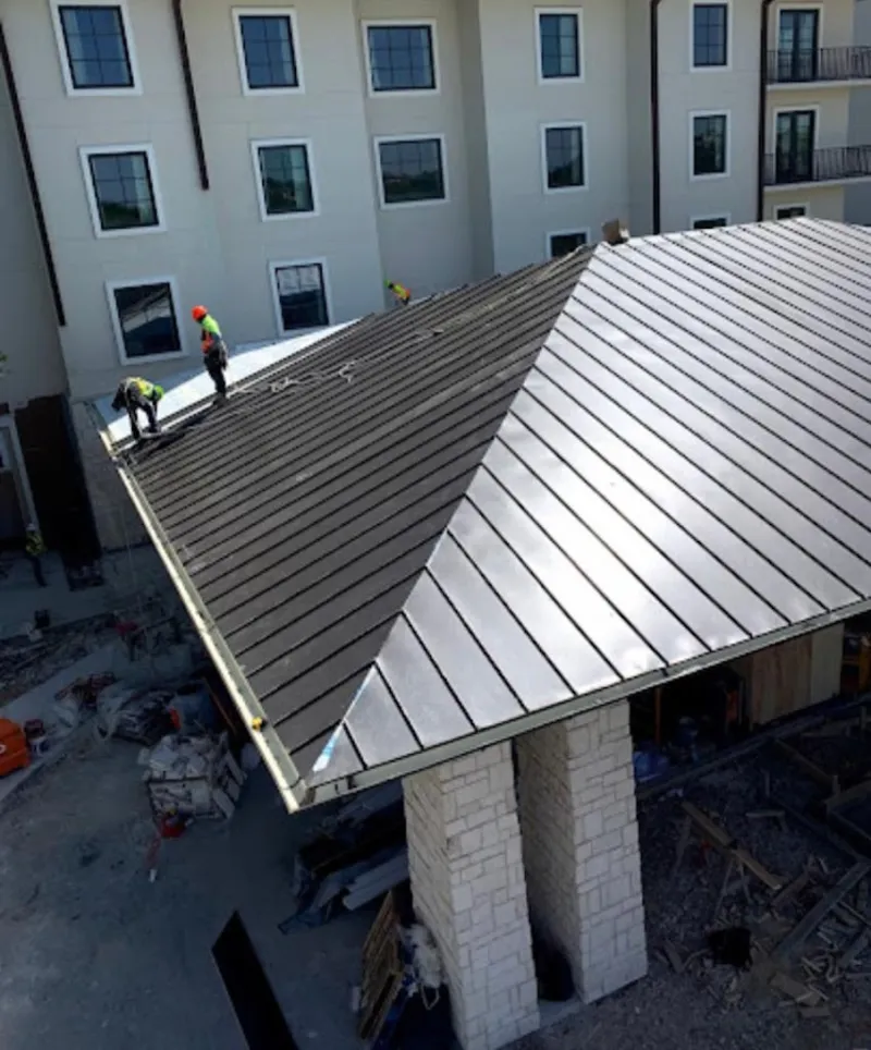 Crew installing standing seam metal roof panels on a commercial project in Willoughby Hills
